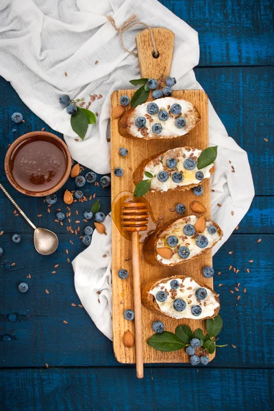 Sandwiches met zachte kaas en bosbessen op een houten achtergrond. Een gezond ontbijt — Stockfoto