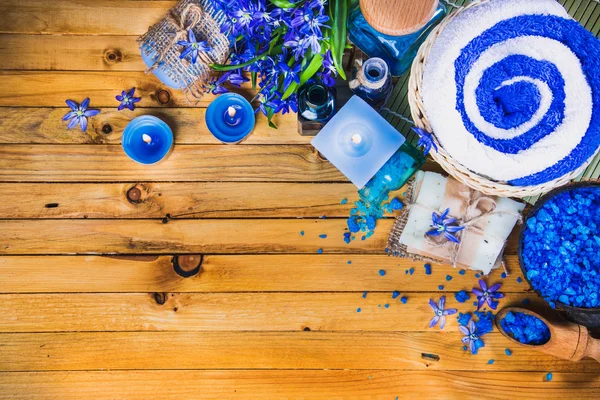 Spa concept in blue tones on a wooden surface: candle, sea salt, flowers, soaps, essential oils. Top view. — Stock Photo, Image