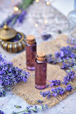 Bokeh arka planında lavanta yağı ve lavanta çiçekleri.