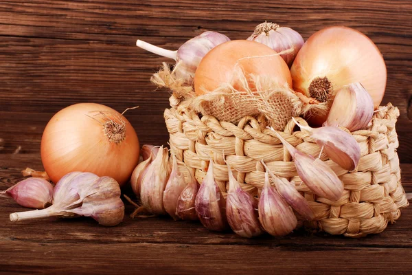 Komposition mit Zwiebel und Knoblauch auf einer Holzoberfläche — Stockfoto