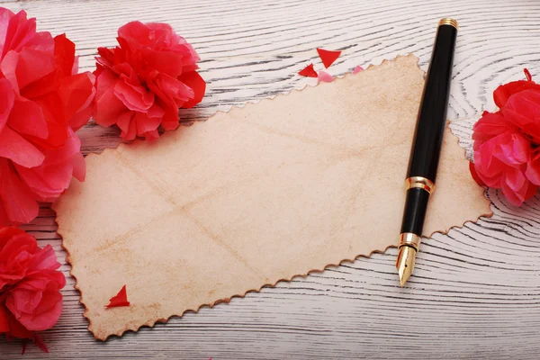 Papel velho, caneta de pena e flores de papel em uma superfície de madeira — Fotografia de Stock