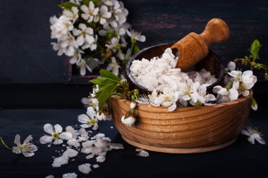 Spa kavramı koyu arka plan üzerinde. Deniz tuz, çiçekli dallar kiraz, aromatik yağlar
