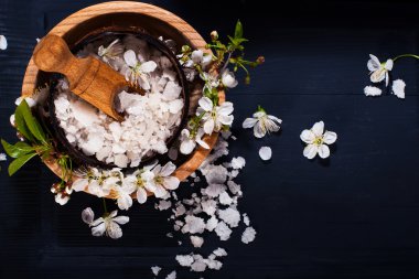 Spa kavramı koyu arka plan üzerinde. Deniz tuz, çiçekli dallar kiraz, aromatik yağlar