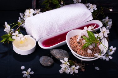Spa kavramı koyu arka plan üzerinde. Deniz tuz, çiçekli dallar kiraz, aromatik yağlar