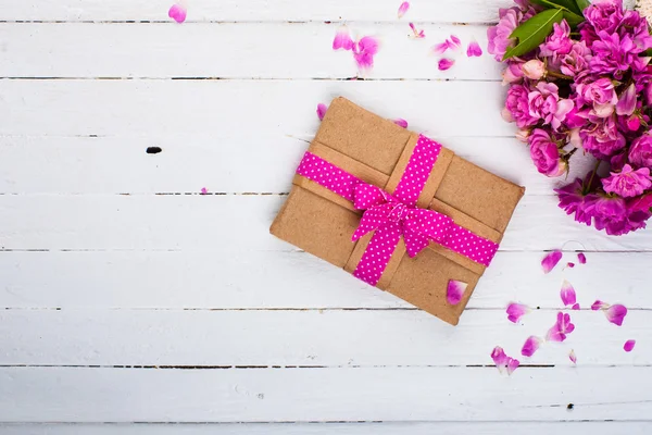 Vintage Hintergrund mit einem Geschenk und Blumen auf einer Holzoberfläche — Stockfoto