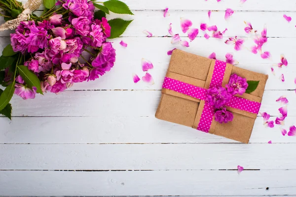 Bir hediye ve ahşap bir yüzey üzerinde çiçekler ile klasik arka plan — Stok fotoğraf