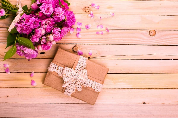 Vintage Hintergrund mit einem Geschenk und Blumen auf einer Holzoberfläche — Stockfoto