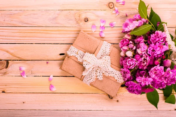 Vintage Hintergrund mit einem Geschenk und Blumen auf einer Holzoberfläche — Stockfoto