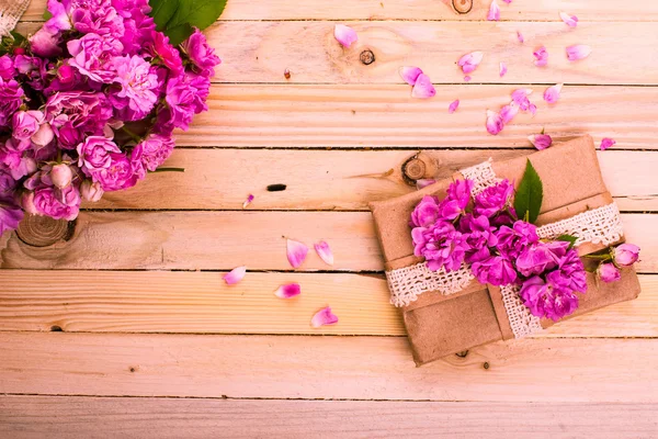 Vintage Hintergrund mit einem Geschenk und Blumen auf einer Holzoberfläche — Stockfoto