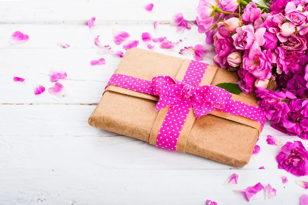 Bir hediye ve ahşap bir yüzey üzerinde çiçekler ile klasik arka plan — Stok fotoğraf