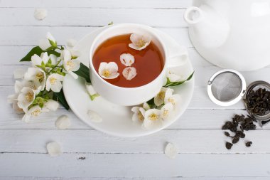 A cup of green tea with jasmine on a white surface