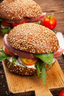 Burger pastırma, roka ve domates ahşap rustik arka plan üzerinde