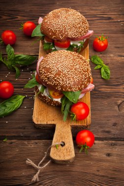 Burger pastırma, roka ve domates ahşap rustik arka plan üzerinde