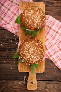 Burger pastırma, roka ve domates ahşap rustik arka plan üzerinde