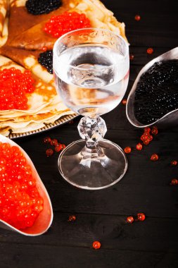 Bir bardak votka, kırmızı ve siyah havyar ve krep ahşap arka plan üzerinde