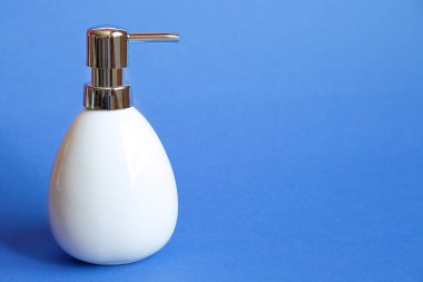 Mavi arkaplana karşı beyaz sabun dağıtıcısı