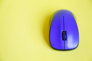 Sarı arkaplandaki mavi kablosuz farenin üst görünümü, kopyalama alanı ile