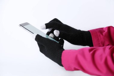 Kışın dokunmatik ekranlar için eldivenli akıllı telefon kullanan bir kadın.