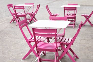 Avrupa 'da bir caddede bir kafede şirin beyaz masalar ve pembe sandalyeler.