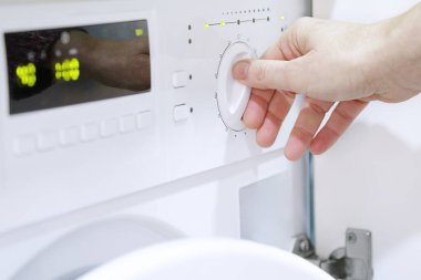 Evde çamaşır makinesi kullanan bir kadın.