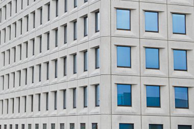Modern bir binada, gökyüzü yansıyan birkaç pencere.