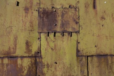 Soluk sarı boya ve pas kaplı metal levha parçalarından yapılmış çarşaf.