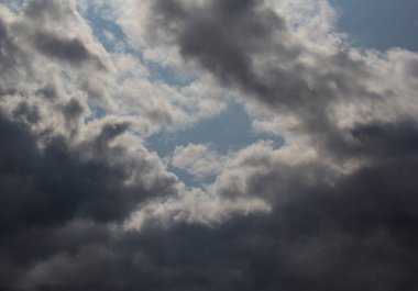 Siyah fırtına bulutlarıyla çevrili mavi bir gökyüzü.