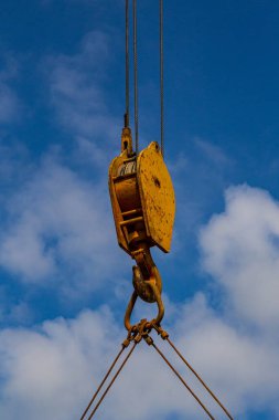 Gökyüzünün arka planında asılı duran bir vinç kancası..