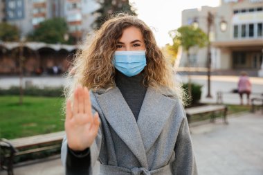 Sosyal mesafeni koru. Virüs korumalı kadın yüz maskesi, jest yapıp enfeksiyonu durdurduğunu gösteriyor. Coronavirus COVID-19 salgın ve sağlık konsepti. 