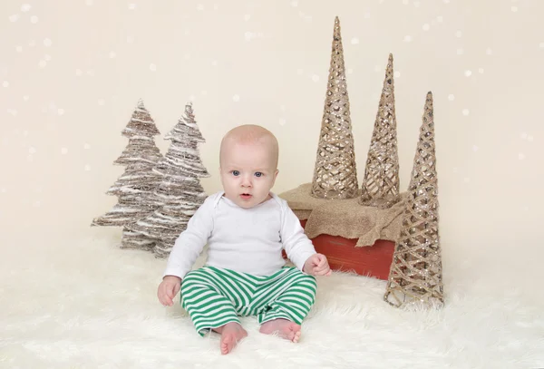 Weihnachtsbaby im Kunstschnee mit Bäumen und Zapfen — Stockfoto