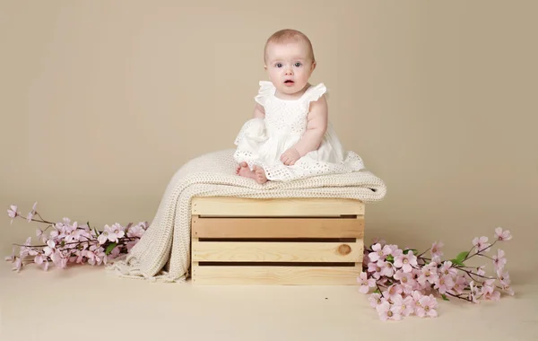 Meisje van de baby met bloemen van de kersenbloesem in de lente jurk op Blanke — Stockfoto