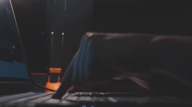 Gece geç saatte bilgisayar klavyesine yavaşça basan iki parmağın görüntüsünü kapat