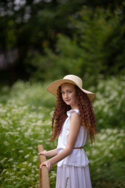 Çiçek açan bir meyveyle piknikte hasır şapkalı tatlı kırmızı kız.