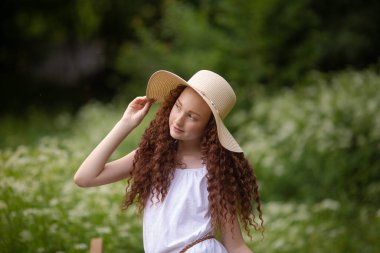 Çiçek açan bir meyveyle piknikte hasır şapkalı tatlı kırmızı kız.