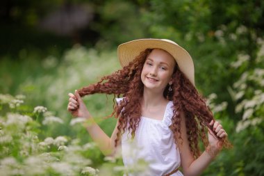 Çiçek açan bir meyveyle piknikte hasır şapkalı tatlı kırmızı kız.