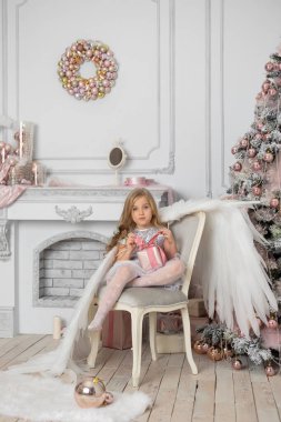 Stüdyoda, Noel ağacının yanında, sarı saçlı, melek kanatlı ve Noel topları olan küçük tatlı bir kız.