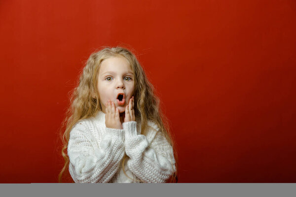 Little cute girl in the studio on a red background with Christmas toys