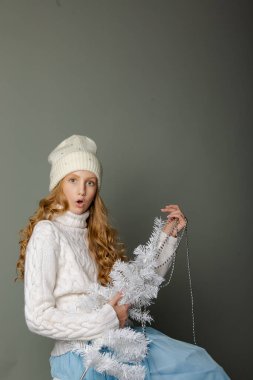 Gri arka planda beyaz şapkalı tatlı sarışın genç kız.