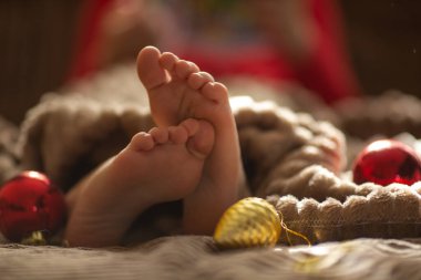 Noel ağacında oyuncaklarla battaniyenin altında bebek bacakları
