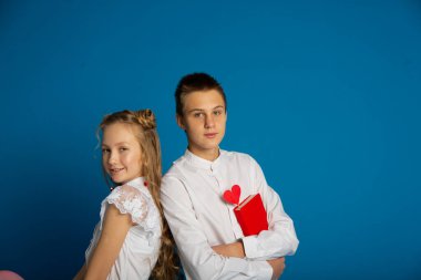 Birkaç okul çocuğu Sevgililer Günü 'nde mavi arka planda ergen oluyor.