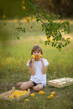 Beyaz tişörtlü, sarı saçlı, yeşil limonlu, ağaçların altında tatlı bir kız.