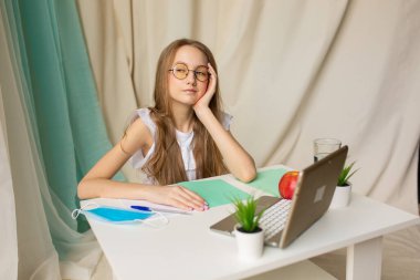 Sevimli liseli kız ödevlerini uzaktan yapıyor ve tarafsız bir geçmiş üzerine dersler dinliyor.