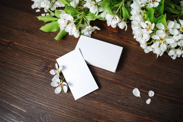 Blank white business cards and flowers on wooden background. Branding ID template.