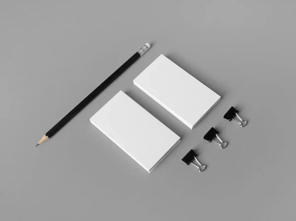 Blank business cards, pencil and paper clips on gray paper background. Stationery mock up.