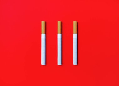 Kırmızı arka planda üç sigara. Düz yatıyordu.