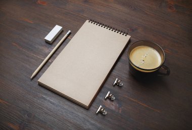Kapalı not defteri, kalem, silgi ve tahta masa arkasındaki kahve fincanının fotoğrafı. Tepkili tasarım modeli. Kırtasiye malzemeleri. Tasarımınızı yerleştirmek için şablon.