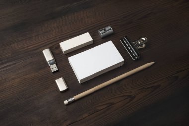 Ahşap masa arka planında boş damgalama kimliği var. Kartvizit, kalem, silgi ve flash disk. Şirket kırtasiye şablonu.