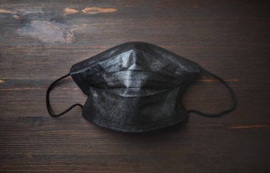 Ahşap arka planda siyah tıbbi koruyucu maske. Corona virüs koruması. Üst Manzara. Düz yatıyordu.