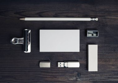 Ahşap arka planda boş kırtasiye seti. Kartvizit, kalem, silgi ve flash disk. Üst Manzara. Düz yatıyordu.