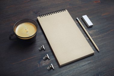 Boş Kraft defteri, kahve fincanı, tahta arka planda kalem ve silgi. Damgalama modeli.